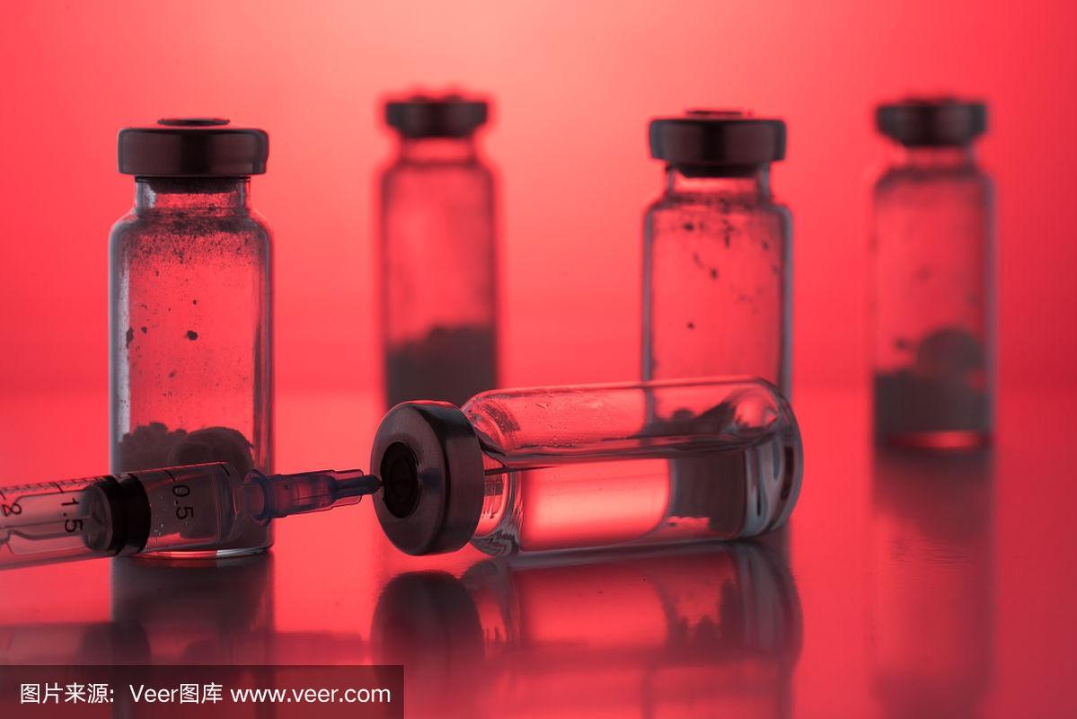 红色背景上带一次性塑料注射器的抗生素注射瓶
